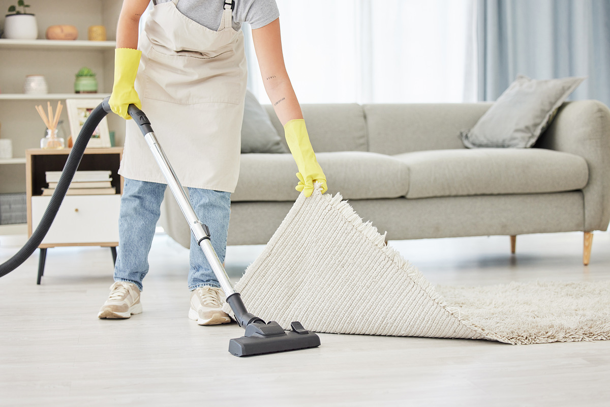 Carpet, person and vacuum with cleaner, home and remove dust for hygiene, bacteria and lounge. Dirt, worker and maid with cleaning equipment, mat and apartment with housekeeping and spring cleaning.