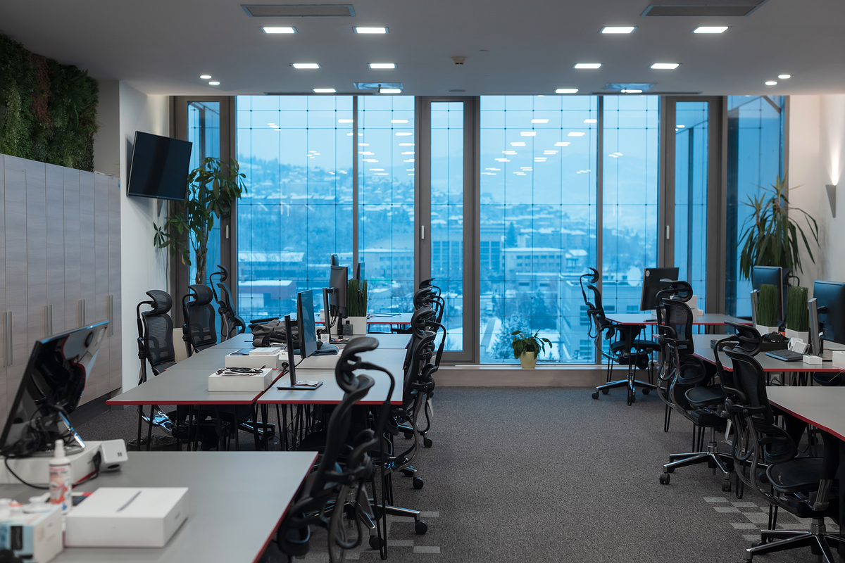 Front view of coworking office interior with workplaces, blank picture frame on wall and computer. . High quality photo