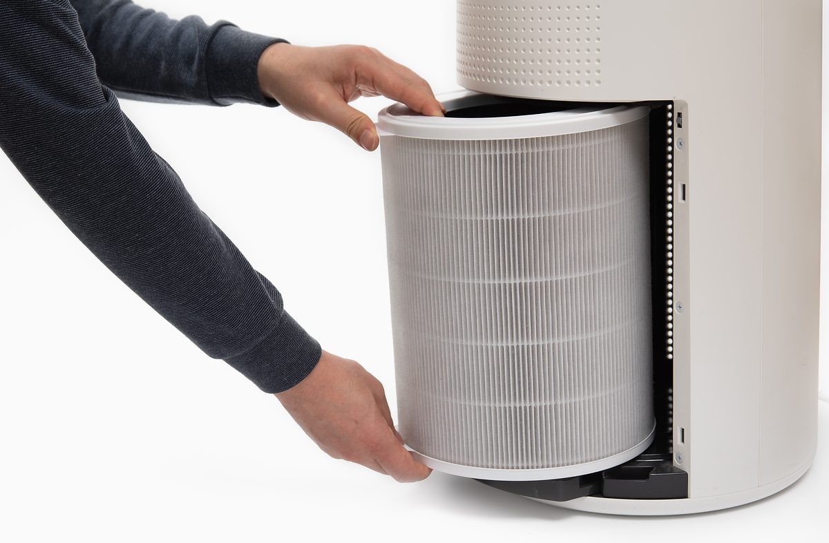 A man's hand turning an air purifier's filter into a new one