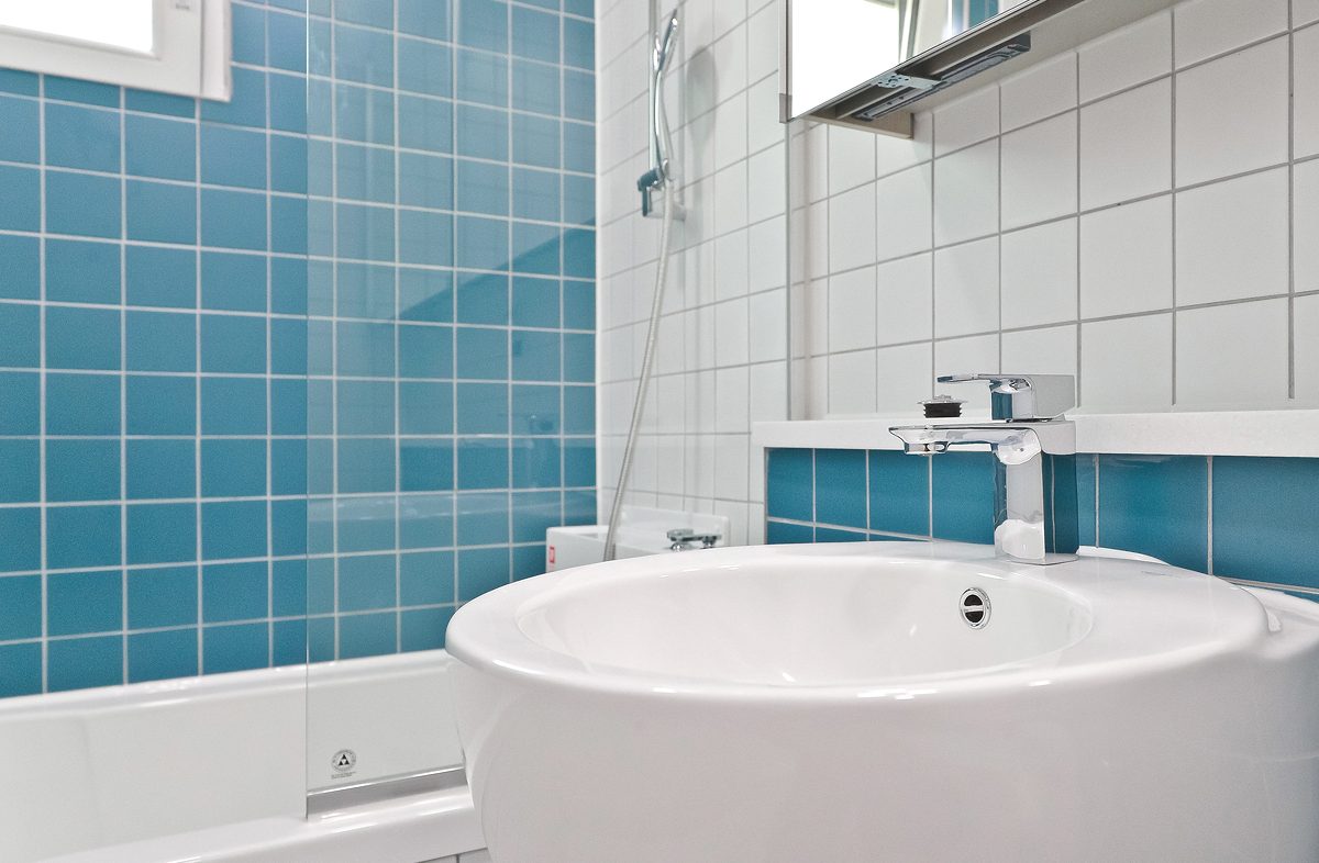 A bathroom finished with square blue tiles, giving it a refreshing feel and neatness