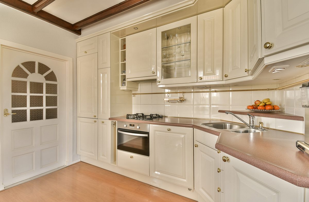 Interior of modern open plan kitchen with white cabinets and stainless steel sink at home