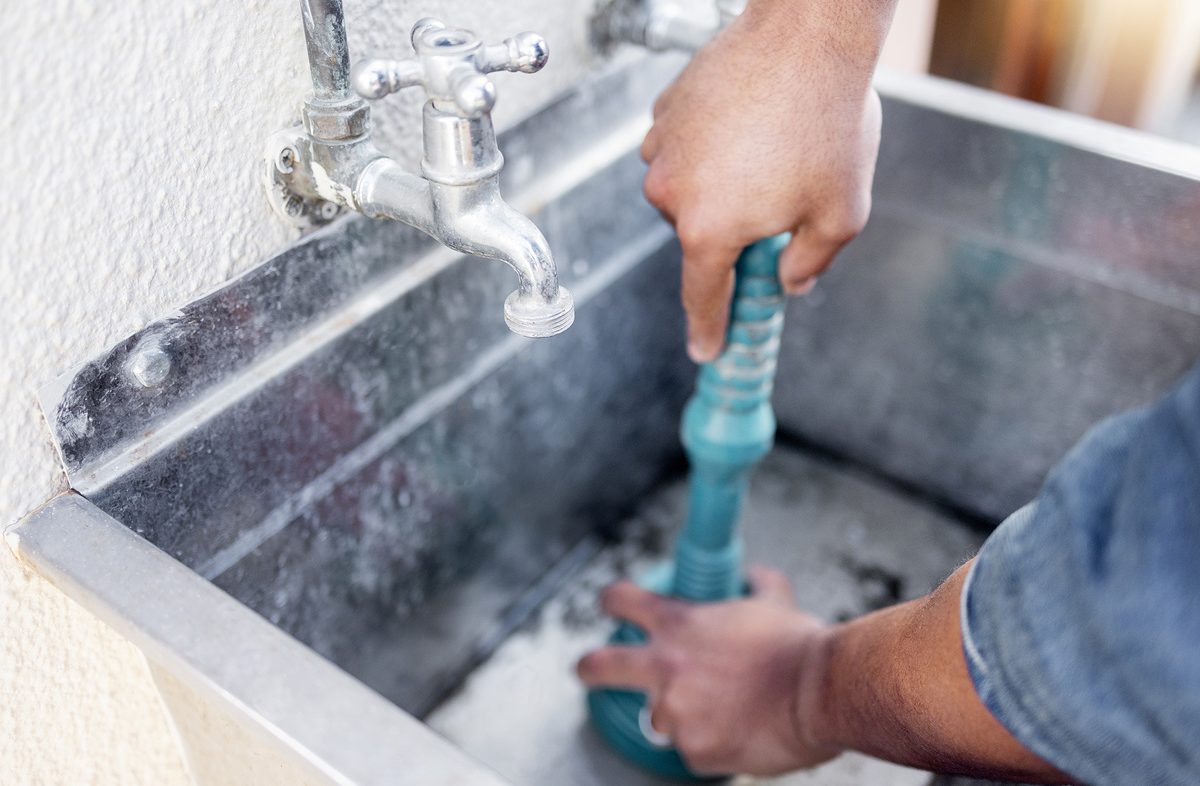 Plumber, drain and man with plunger for sink, maintenance and repairs, blockage or cleaning. Plumbing, drainage and professional handyman fixing, clear and working with equipment for system fix.