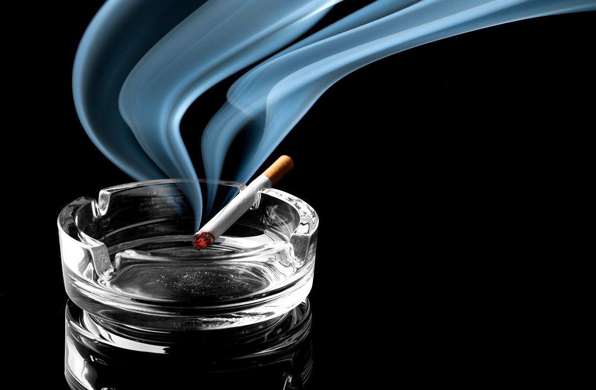 Closeup of cigarette on ashtray with a beautiful wisp of smoke