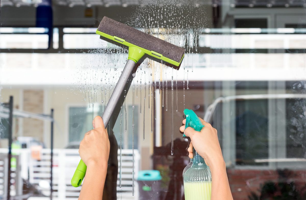 Hands of young woman wipe the glass with a glass cleaner-hobbies and leisure concepts.