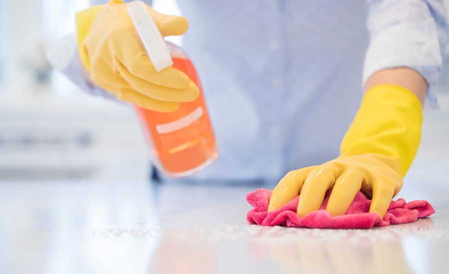 Close Up Of Woman Using Spray Polish To Clean Kitchen Surface